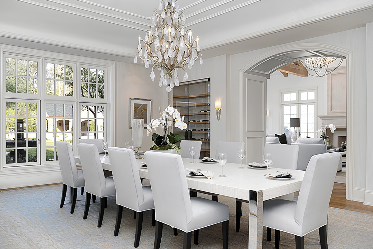 a dining room table with white chairs and a chandelier